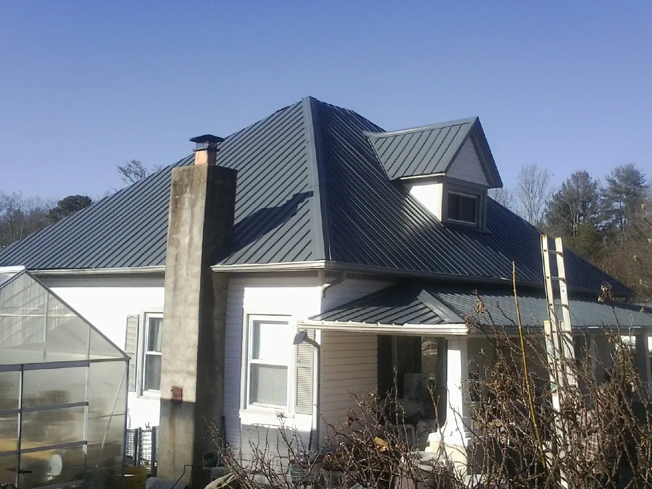 Dark blue standing seam metal roof on a white farmhouse with dormer — Slate & Tile Roof Repair by Roofing Brothers in Penns Grove