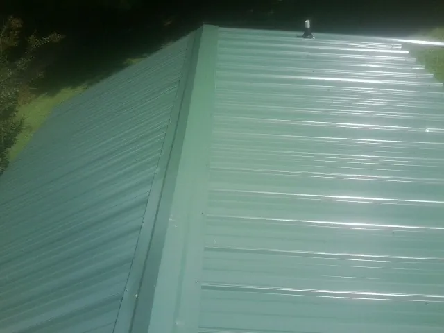 New green metal panels meeting at the ridge of a roof — Flat Roof Repair work by our crew in Penns Grove