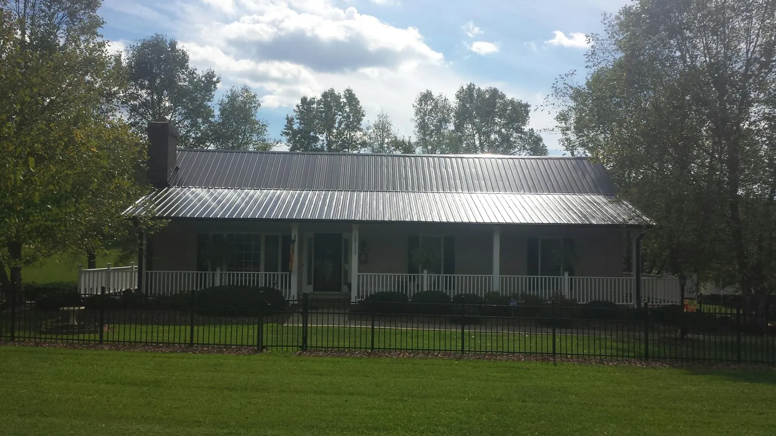 Gray metal roof on a brick ranch with a full width front porch — Gutter Guard Installation work by our crew in Penns Grove