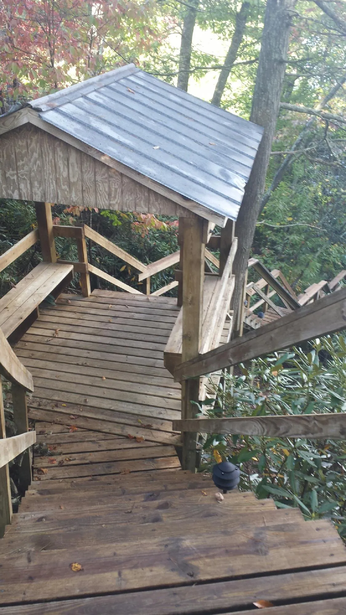 Metal roofed shelter over wooden steps on a wooded walkway — Skylight Repair & Installation work by our crew in Penns Grove