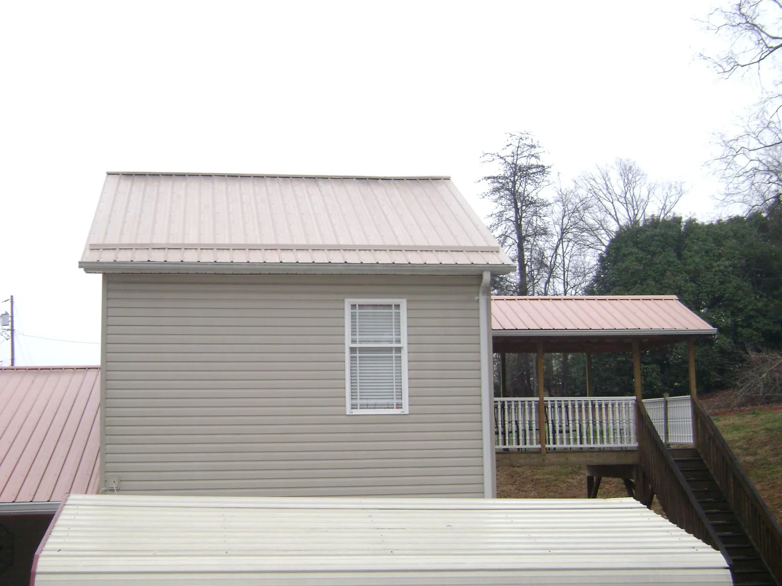 Tan metal roofs on a two story addition and attached porch, from a Roof Replacement job in Penns Grove