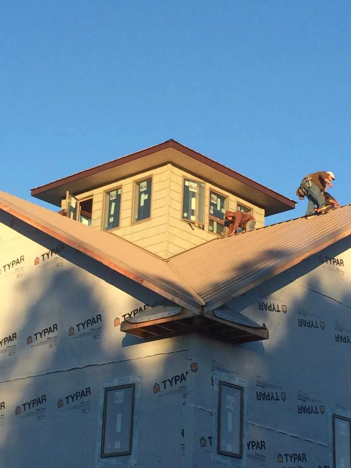 Roofers working around a rooftop cupola on a new metal roof at sunset — Roof Waterproofing in Penns Grove by Roofing Brothers